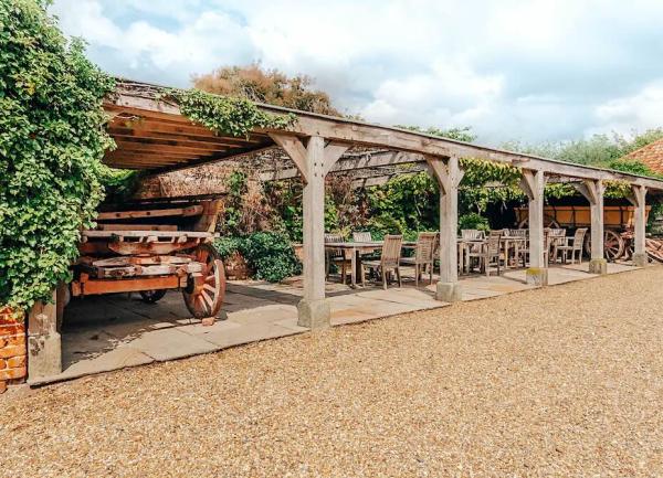 A terraced arbour with dining tables and old farm carts at either end.