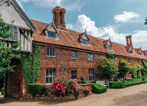A row of 18th-century brick cottages with ornate chimneys and manicured front gardens.