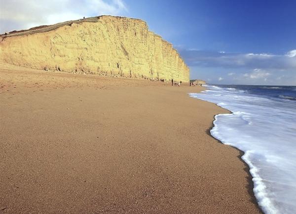 Waves roll ashore beneath cliffs on Chesil Beach