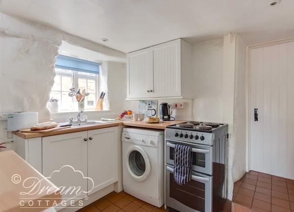 Kitchen corner with oven, washing machine and sink.