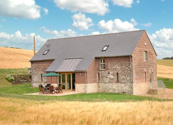 Exterior of a brick built barn conversion surrounded by open fields.