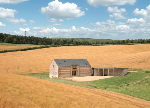 An isolated barn conversion surrounded by ripened wheat fields