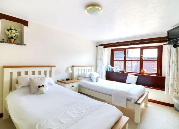 A twin bedroom with bedside table and a window seat.
