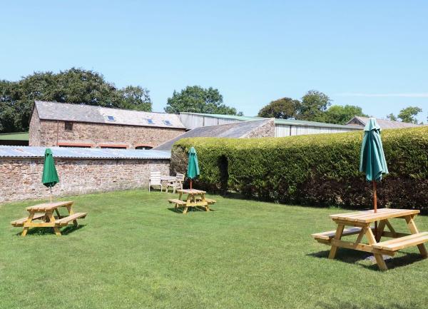 A spacious lawn with picnic tables surrounded by a hedge