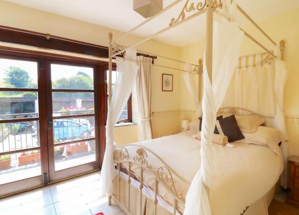 A 4-poster bed in a bedroom with French windows to a balcony.