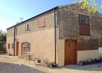 Exterior of a Cambridgeshire, brick built barn conversion in a courtyard.