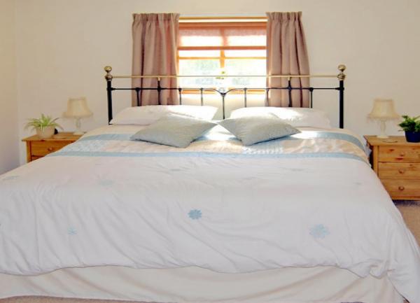 Double bedroom with brass bed, twin bedside cabinets and table lights.