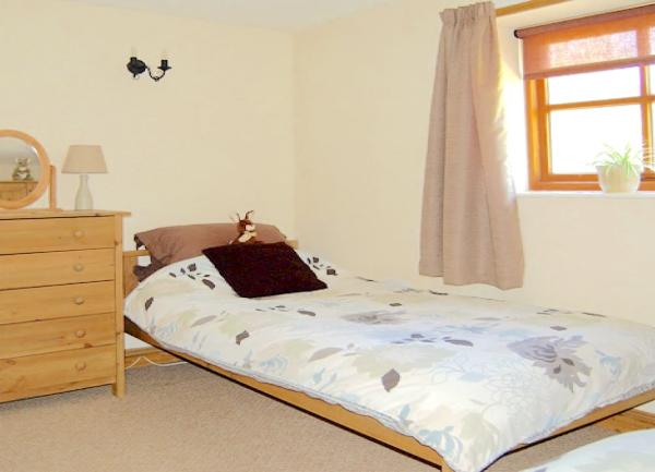 Twin bedroom with beds, chest of drawers and a bedside light.