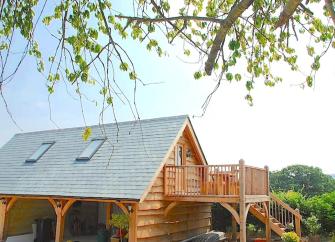 A Swiss-style wooden holiday lodge with a 1st floor deck looks out across lush Somerset countryside.