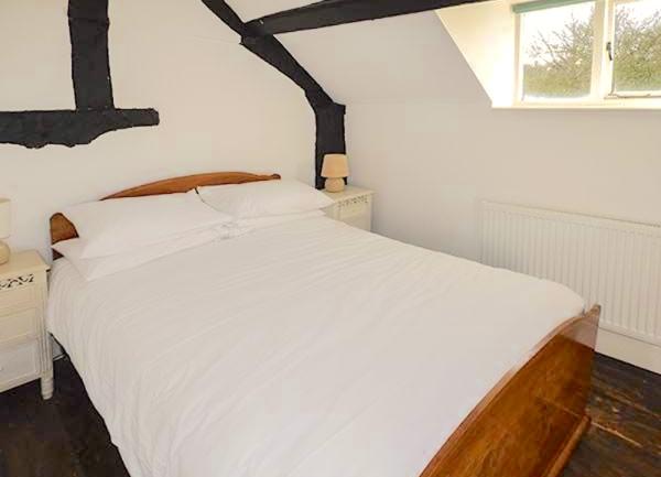 Oak-beamed double bedroom with bed and twin bedside tables with table lamps
