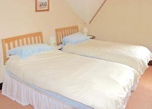 Double bedroom with dressing table and wicker armchair.