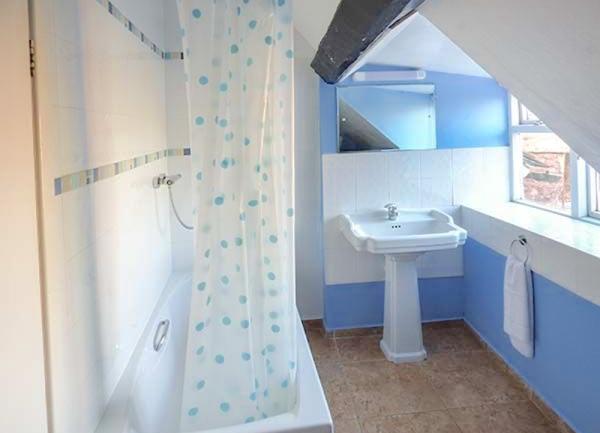 Bathroom with a bath that has an overhead shower.