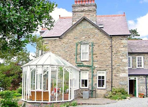 Exterior of a stone country house with a glass sun room.