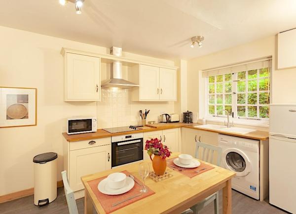 Kitchen with a dining table cooker, washing machine and a tall fridge-freezer.