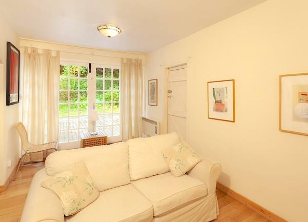 A large sofa in a lounge with French windows that lead to a garden.