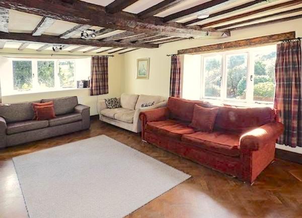 A parquet floored lounge with 3 sofas and a rug.