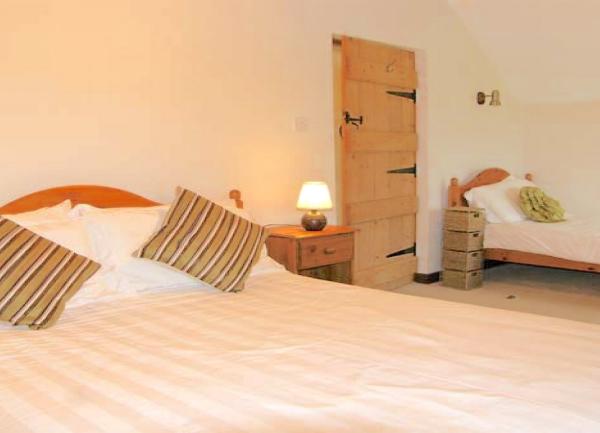 A family bedroom with a doublke and single bed with bedside cabinets and table lights.
