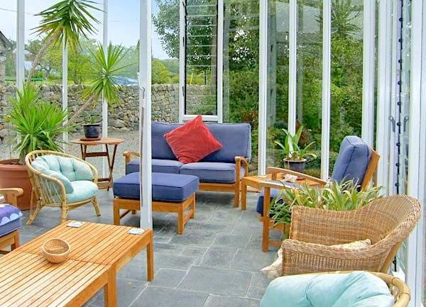 Conservatory with coffee table and Lloyd-Loom-style wicker chairs.