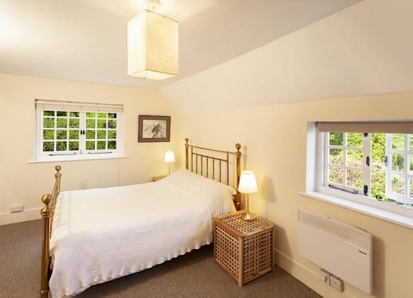Dual aspect double bedroom with a brass bed and bedside tables with lights.