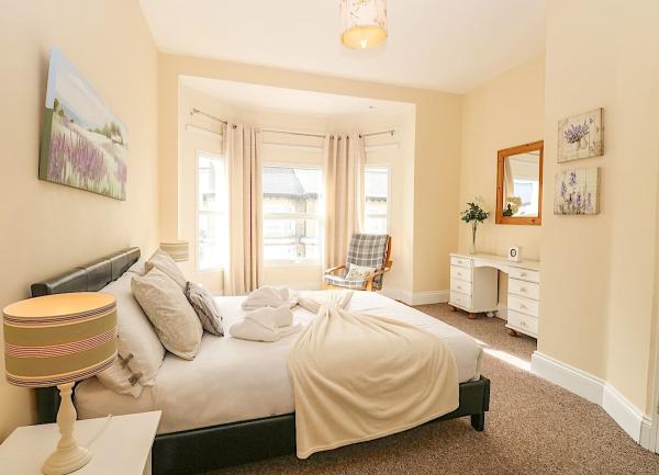 A bay-windowed double bedroom with a bed, dressing table and mirror.
