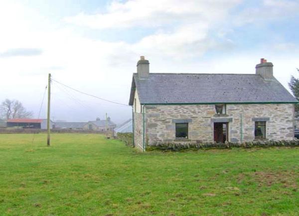 A stone built cottage in Snowdonia overlooking a large field.