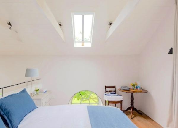 Double bedroom with chest of drawers, side chair and small table.