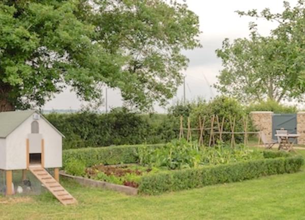 A garden with a vegetable patch and tiny child's playhouse.