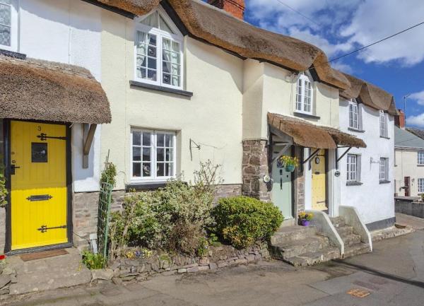 Exterior of a terrace of thatched cottages on an empty village street.