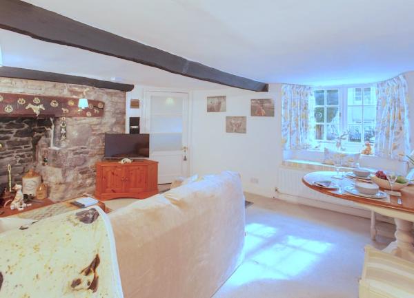 A lounge-diner with inglenook fireplace, TV, sofa and dining table for two.
