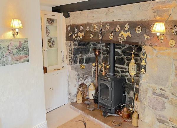 A wood burner in an inglenook fireplace with horse brasses on the beam.