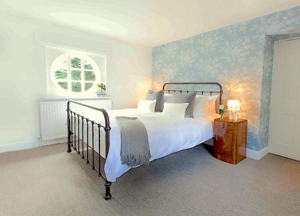 A double bedroom with a circular window and bed with twin bedside cabinets and table lamps.