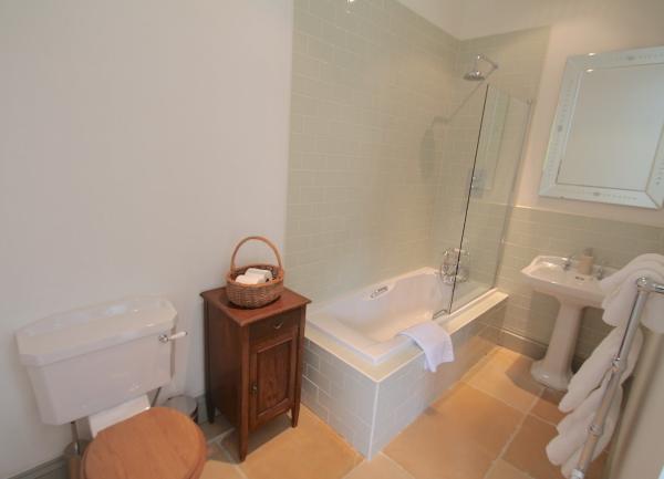 Bathroom with a bath having an overhead shower, washbasin and WC.