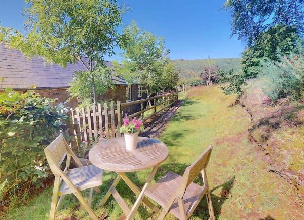 A garden corner with a picnic table and chairs alongside The Hayloft cottage.