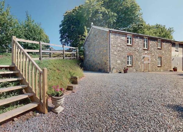 Exterior of a barn conveersion overlooking a large shinlge courtyard with plenty of parking space.