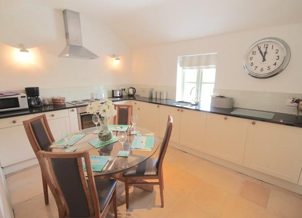 A kitchen with nodern units and appliances on three sides with a dining table in the centre