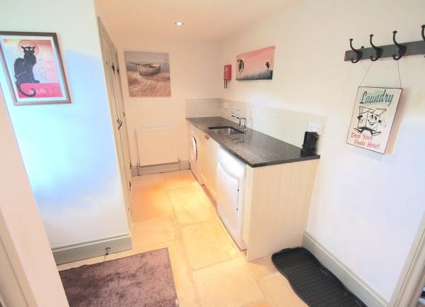 A utility room with washing machine, tumble-dryer, sink and coat hooks