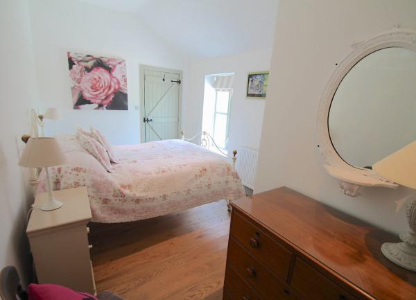 Doubke bedrooom with ches of drawers, twin bedside cabinets with table lights and a mirror.