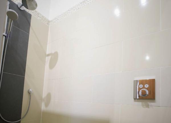 A shower head in a fully tiled, walk-in wet room.