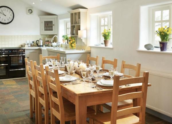A kitchen diner with a dining table laid for dinner and the kitchen in the background.