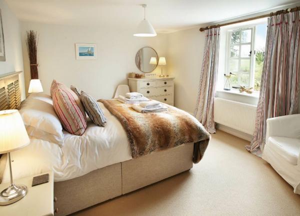 This is a double bedroom with a large bed with scatter cushions, a chest of drawers, and bedside tables with table lamps.