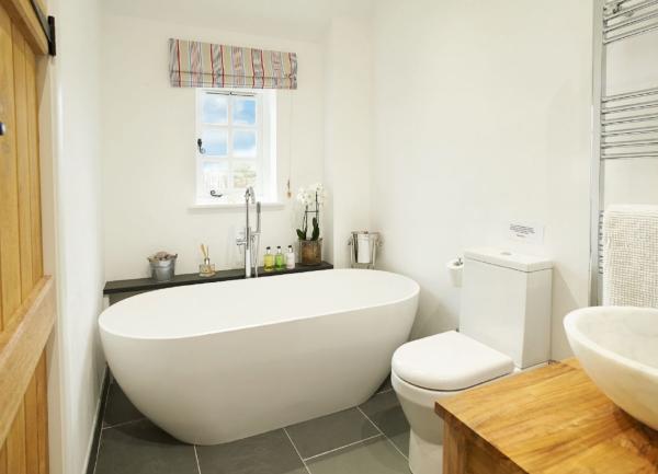 A slate-tiled bathroom with a stylish match of bath, washbasin and WC.