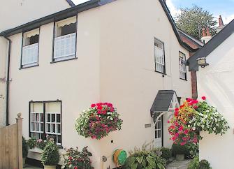 2-Storey cottage exterior with hanging flower baskets.