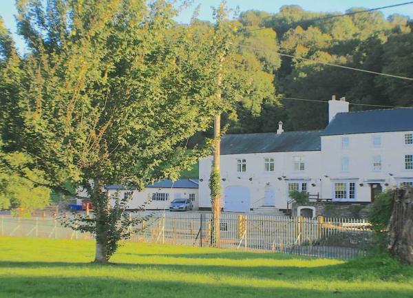 A view of a largeGeorgian House from acrooss a field by a riverbank.