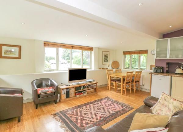 An open plan lounge, dining and kitchen area with a pine floor.