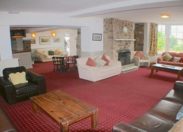 Lounge with 2 sofas and 2 armchairs, coffee tables and a wood burner.