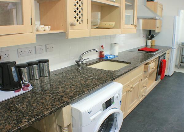 Kitchen with marble worktop, washing machine and kitchen sink.