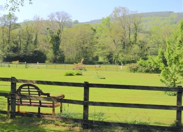 A large tree-fringed field with benches around its edge for picnics and games.