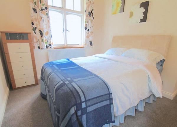 Double bedroom with bed and tall chest of drawers.