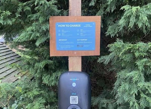 An electric vehicle charging point on a fence post.