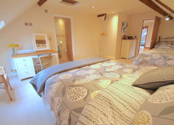 Family bedroom with a double and single bed, wicker easy chair and dressing table.